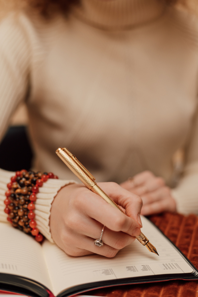 Nő kezében tollal, füzetbe jegyzetel