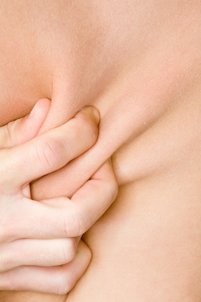 Nő összeszorítja a hasán a zsírt