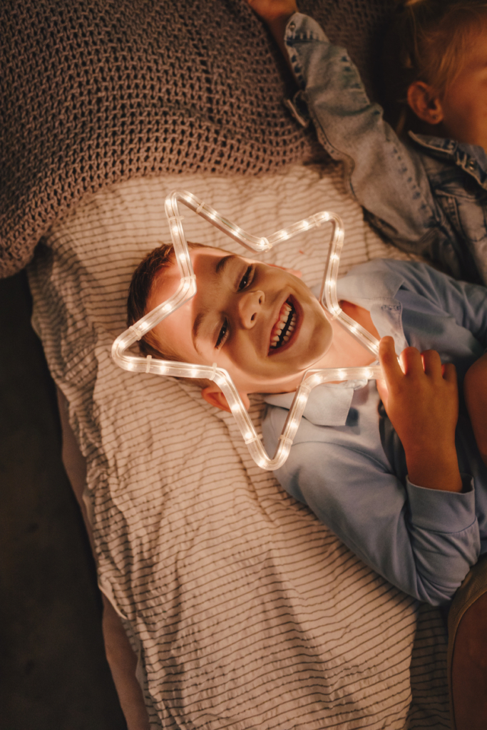 Kisfiú a kezében világító csillag dísszel nevet