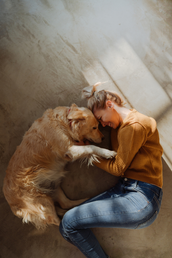 Gazdi és golden retriever összebújva a földön