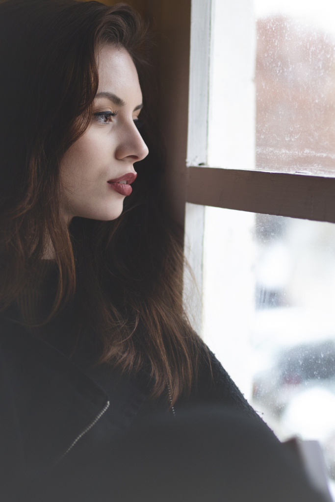 Nő egyedül néz ki az ablakon elgondolkodva
