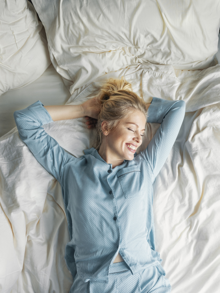 Nő ébredezik reggel a friss levegőjű hálószobában