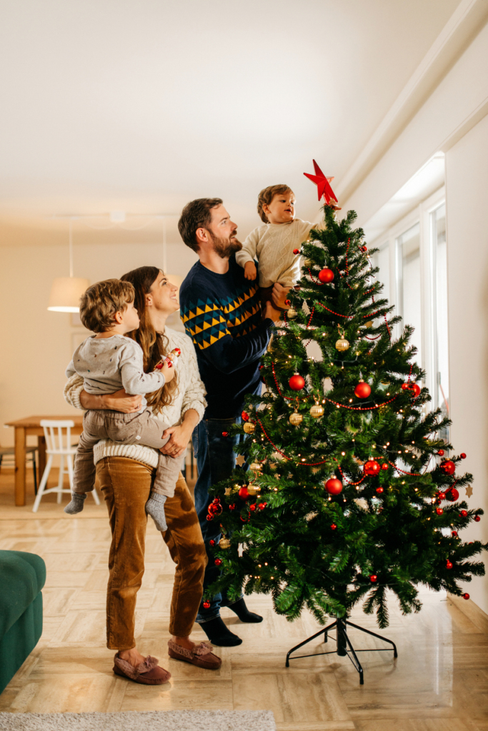A család apa, anya és gyerekek, közösen díszítik a karácsonyfát