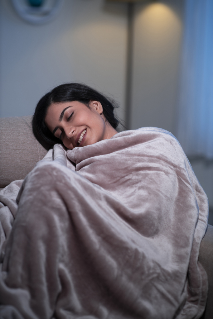 Nő egy takaróba csavarva mosolyogva pihen