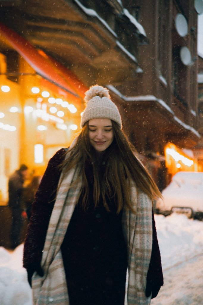 Lány sétál az esti, téli városi forgatagban