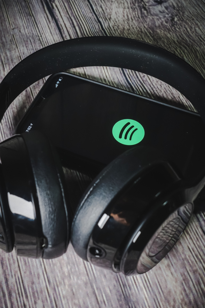 Spotify logó egy Iphone 11 készüléken, mellette egy fejhallgató