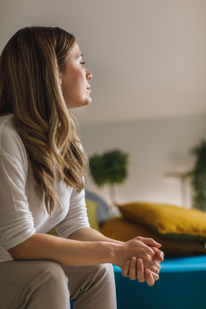 Nő elgondolkodva ül az ágy szélén