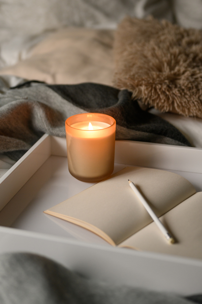 Téli illatgyertya meggyújtva és egy üres oldal a naplóban