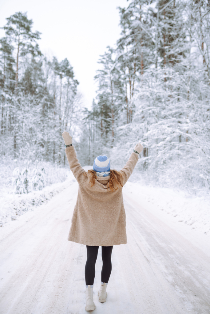 Nő téli sétát tesz a havas fák között