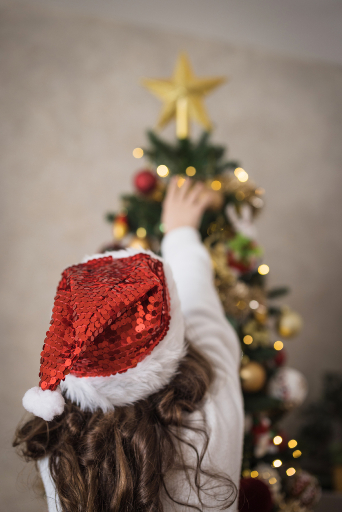 Kislány karácsonyfát díszít