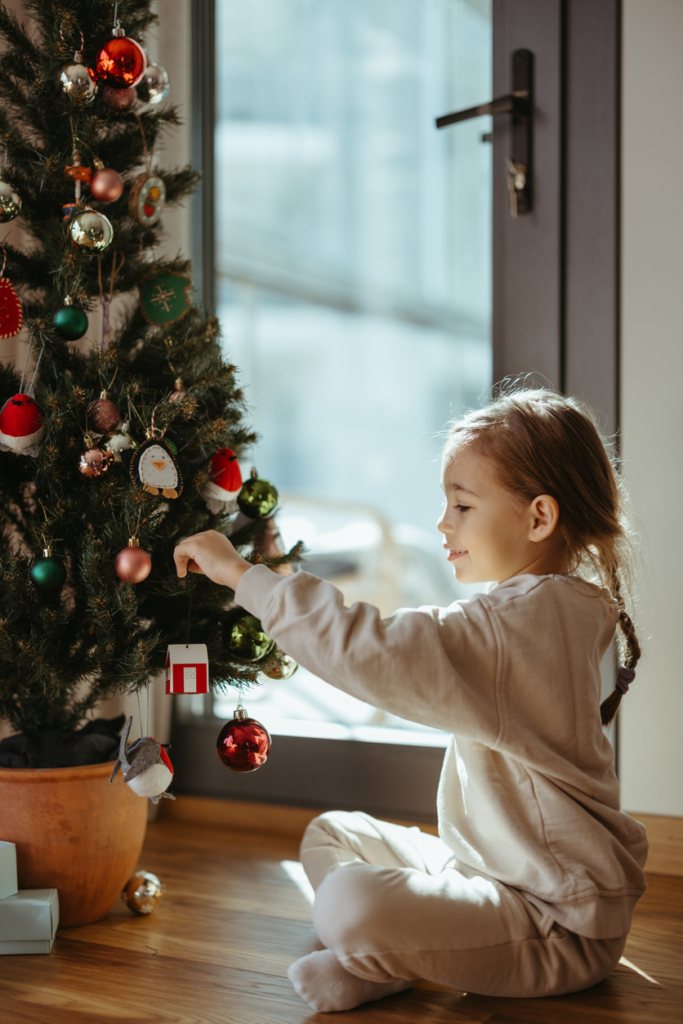 Kislány karácsonyfát díszít