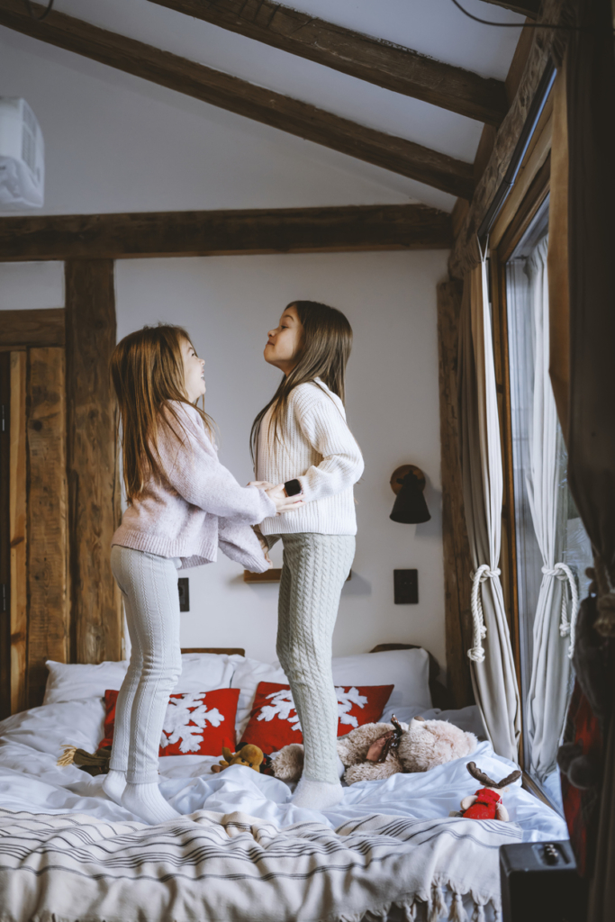 Két kislány ugrál az ágyon