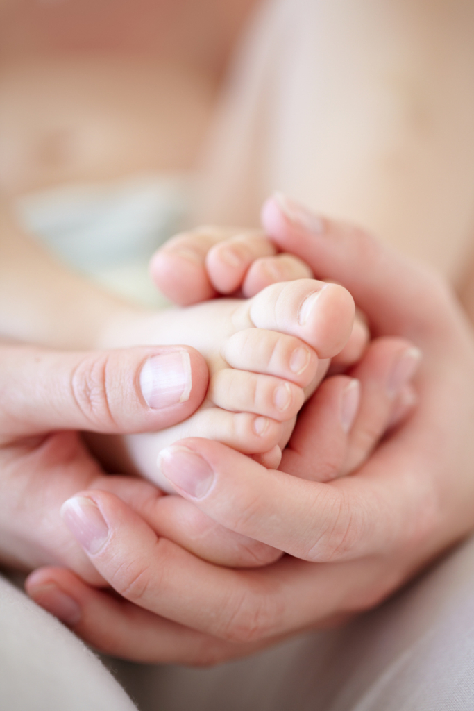 Anya fogja a kisbaba lábát, közeli kép