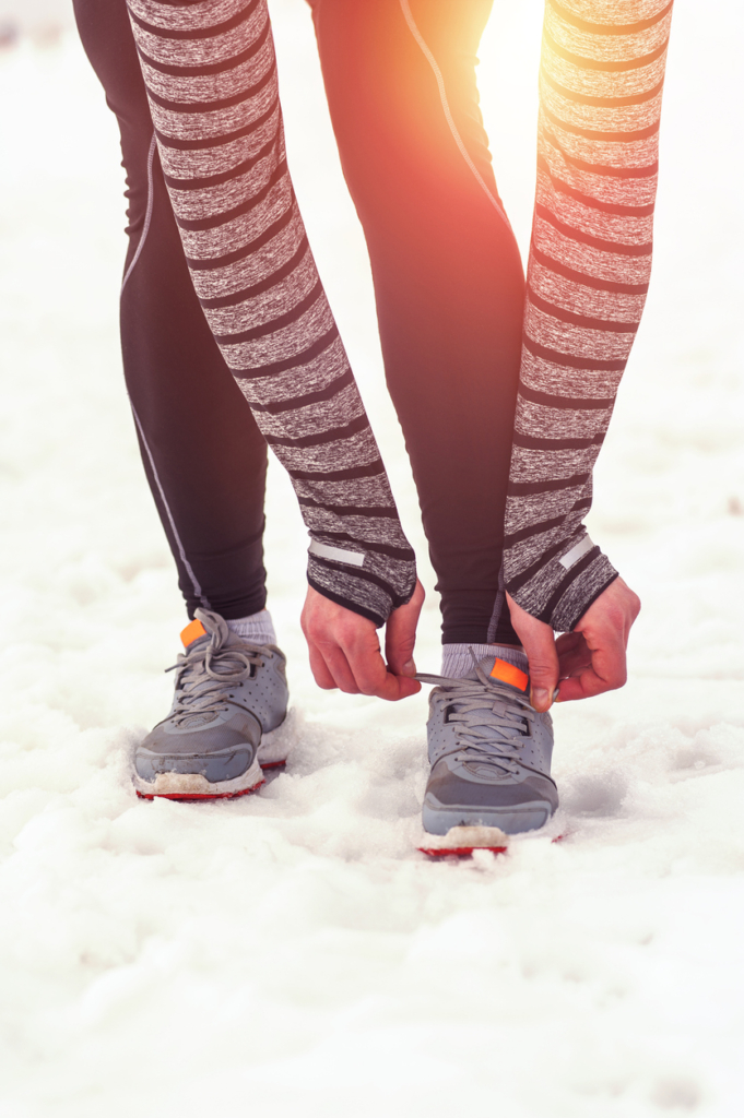 Nő lehajol bekötni a cipőfűzőjét