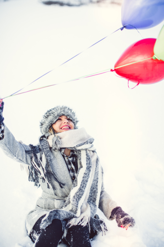 Boldog nő léggömböket enged el a hóban