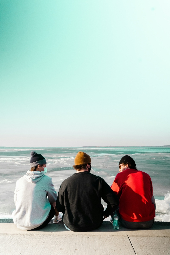 Fiatal srácok háttal ülnek a vízparton