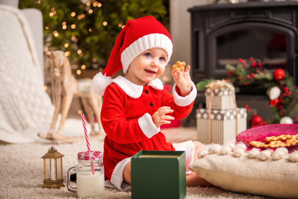 Mikuláscsomagot bontó kisgyermek Mikulás ruhába öltöztetve