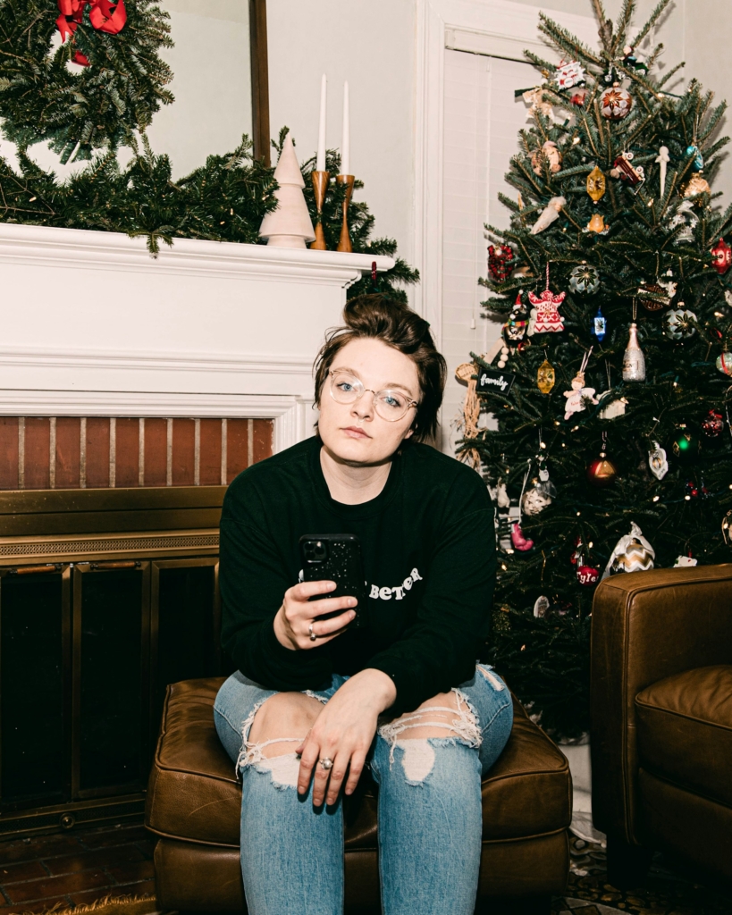 Kiábrándult fiatal nő ül a karácsonyfa mellett