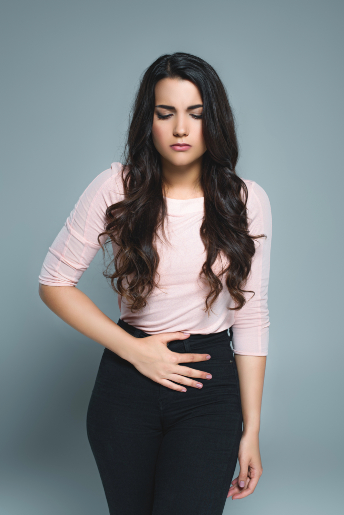 Nő fogja a hasát a fájdalomtól