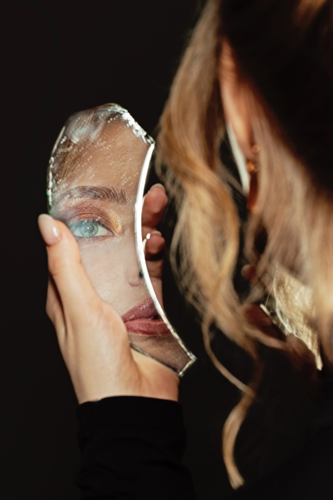 Nő egy darabka törött tükörben nézi az arcát