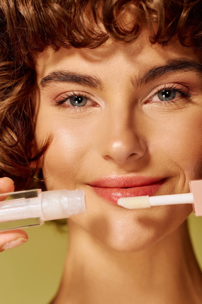 Mosolygós nő egy tubus szájfénnyel a kezében