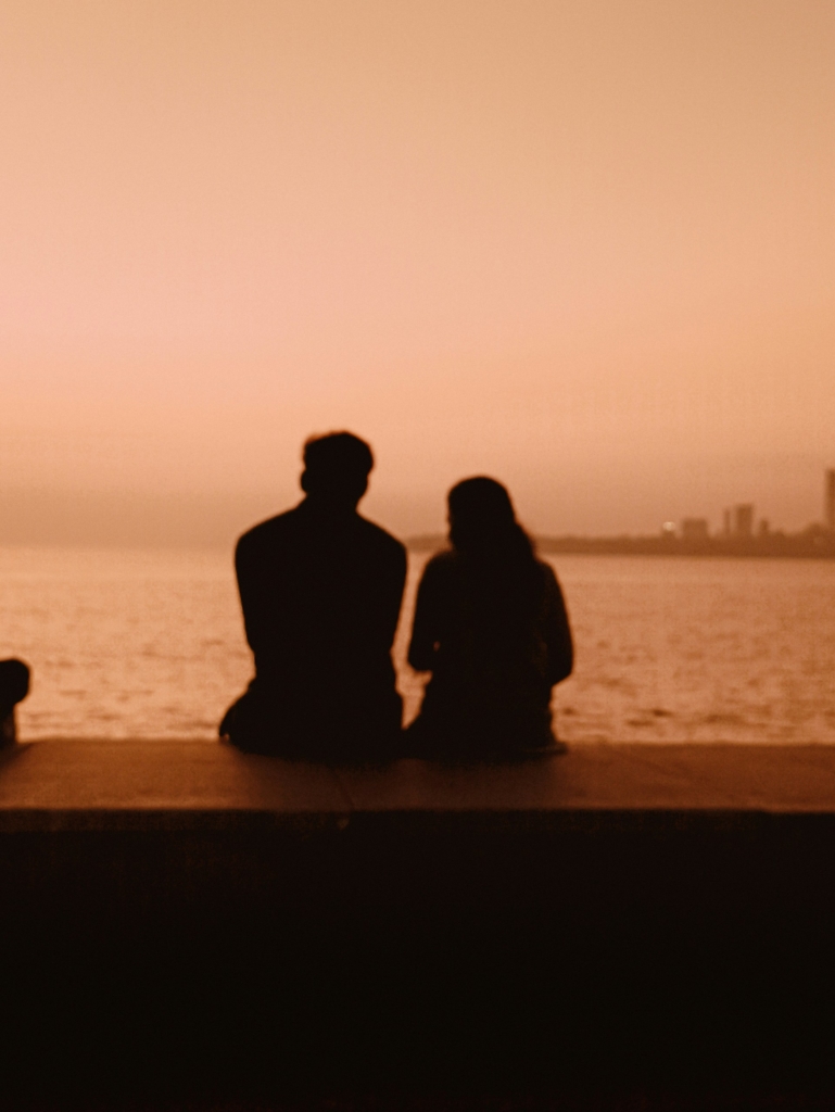 Pár háttal ül a naplementében
