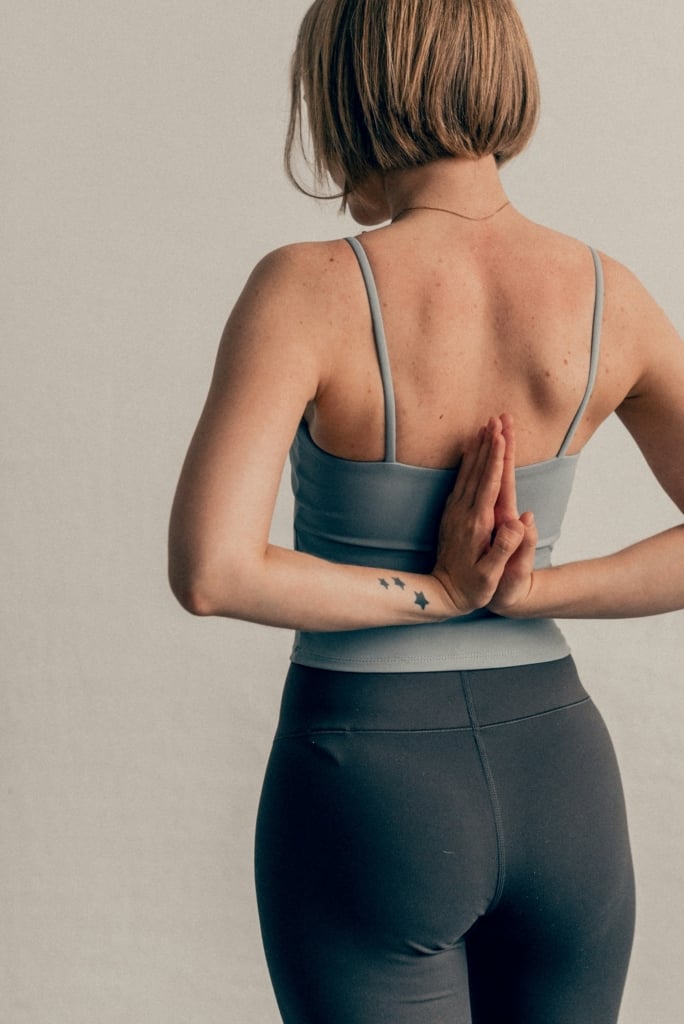 Nő jóga pózban, a háta mögött érinti össze a tenyerét