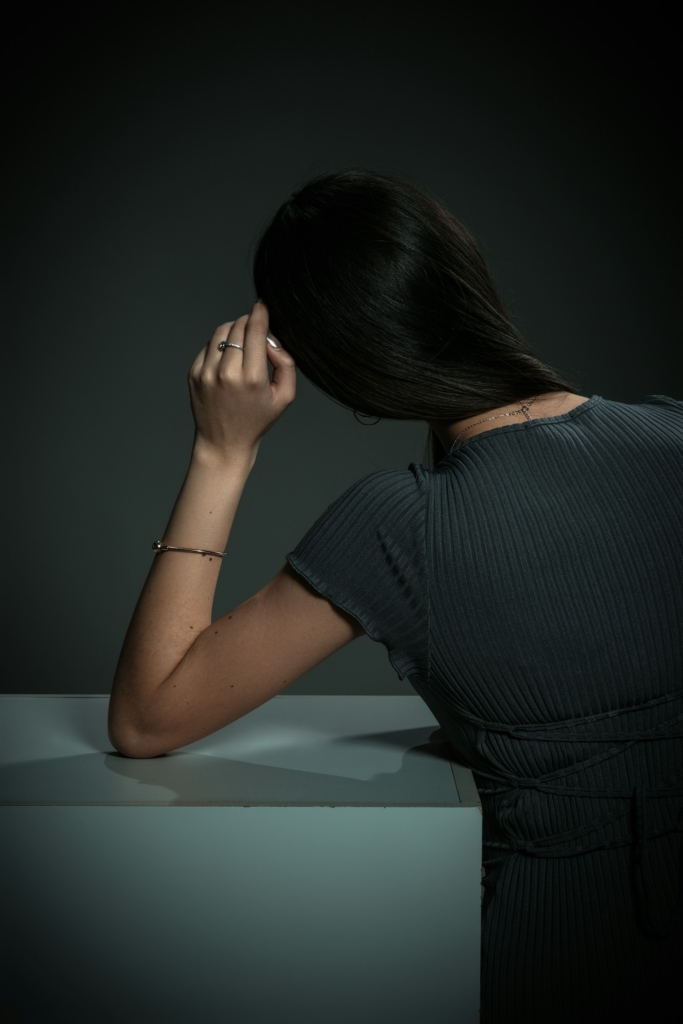 Nő háttal ül és könyököl egy asztalon