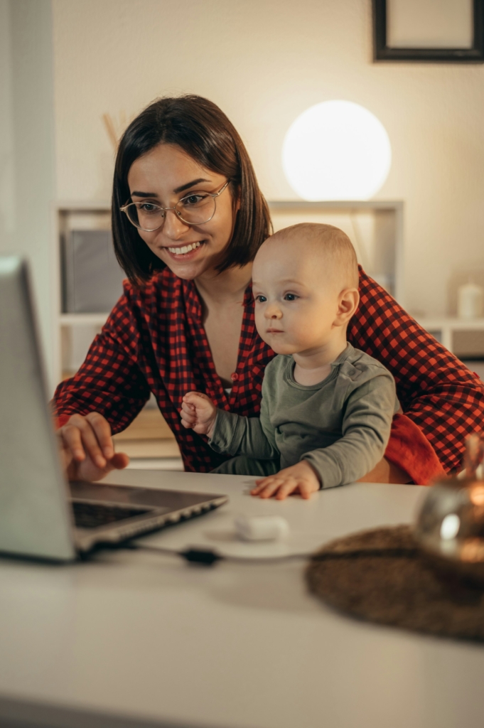 Anyuka az ölében a kisbabájával dolgozik a laptopján