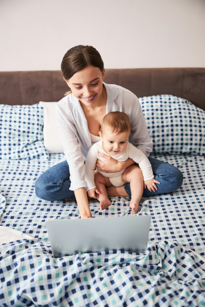 Anya és kisbabája az ágyon laptopozik
