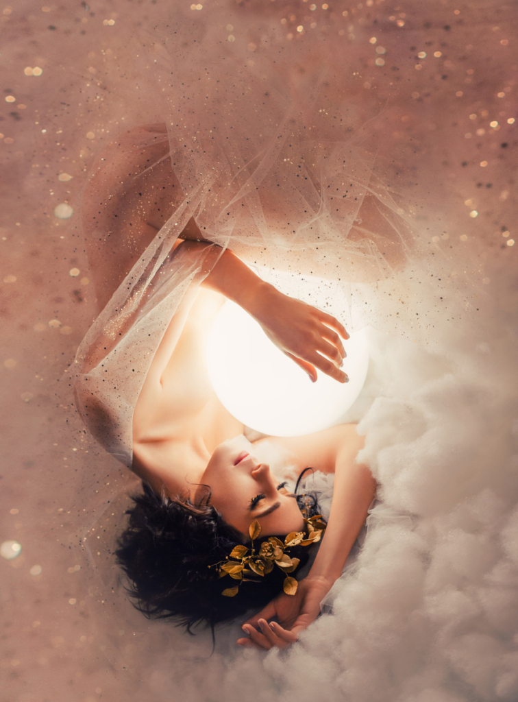 Álomszerű kép egy angyali nőről, aki magához öleli a teliholdat