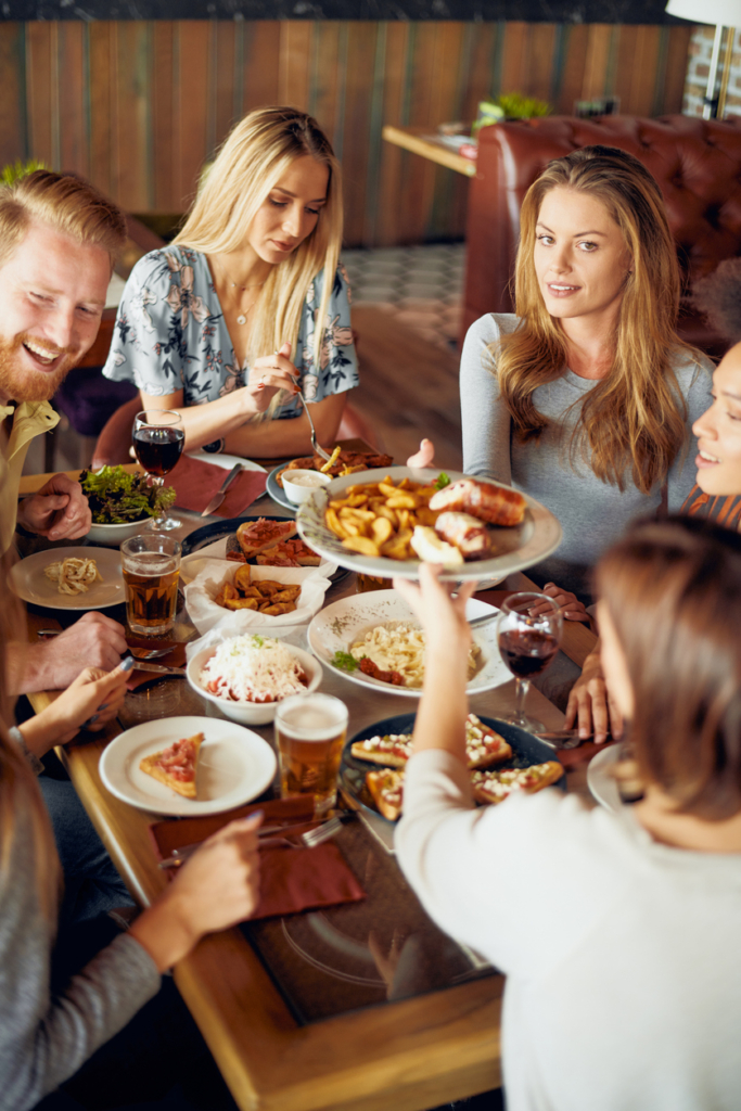 Baráti társaság közösen ebédel és beszélget egy asztalnál az étteremben