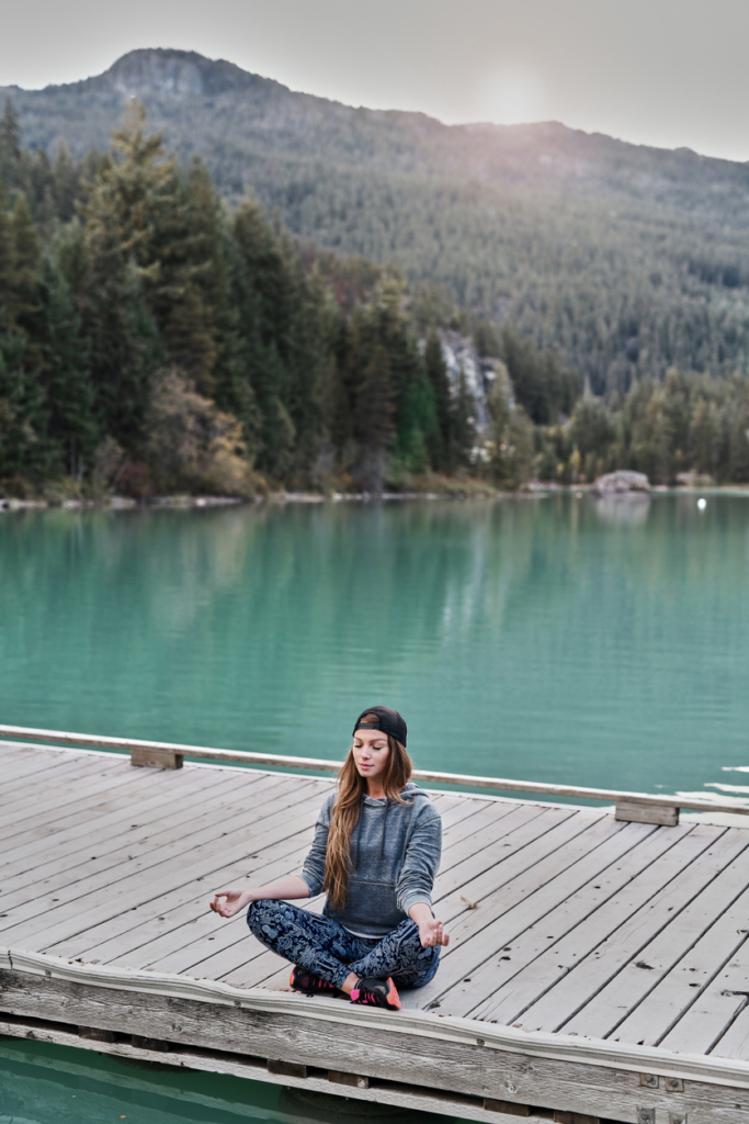 Nő hegyi tó mellett meditál