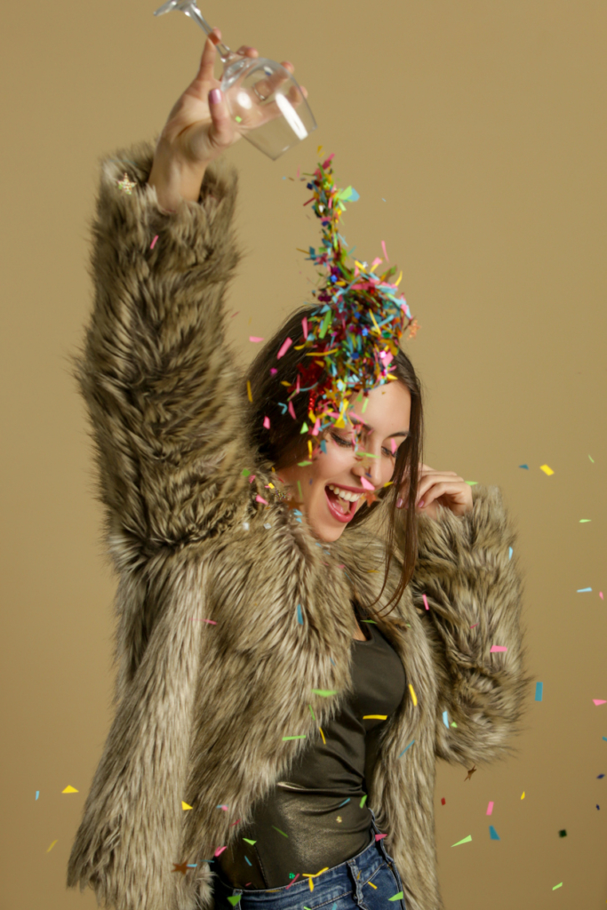 Femme élégante versant des confettis d’un verre