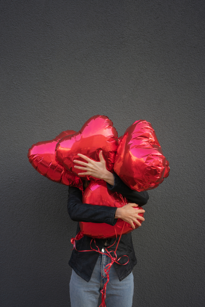 Nő szív alakú lufikat ölel magához