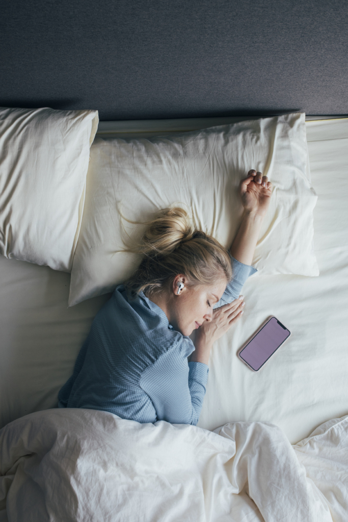 Nő alvás közben zenét hallgat a telefonján