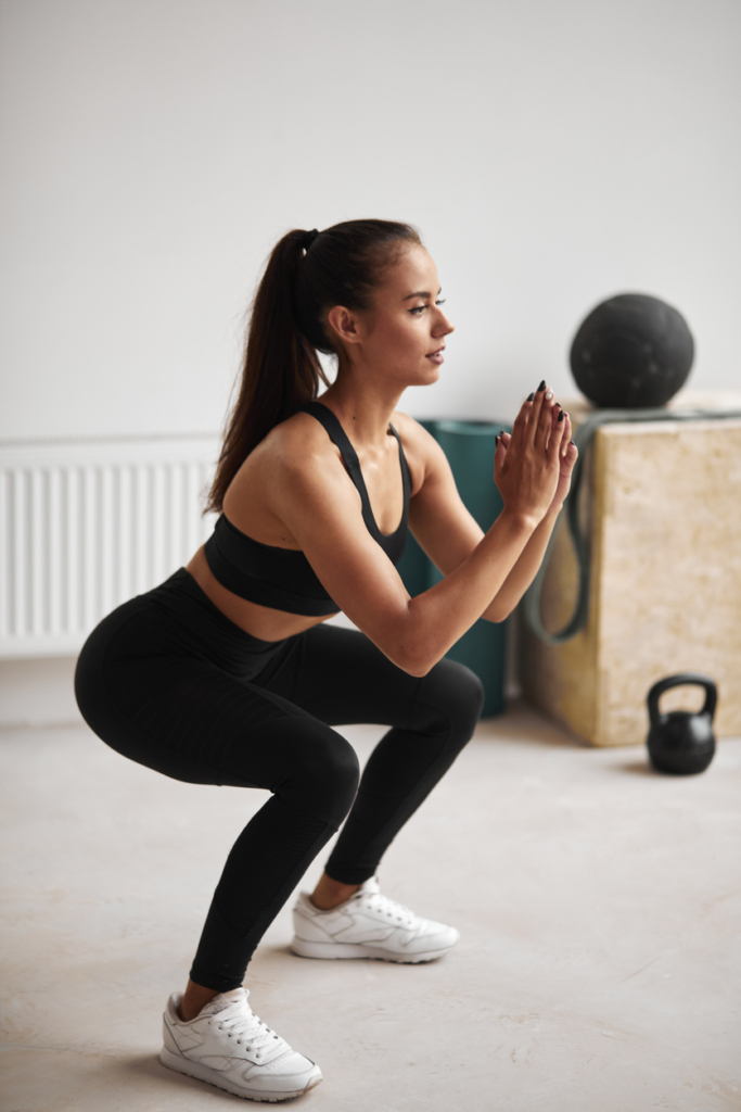 Nő guggolásokat végez egy fitness teremben