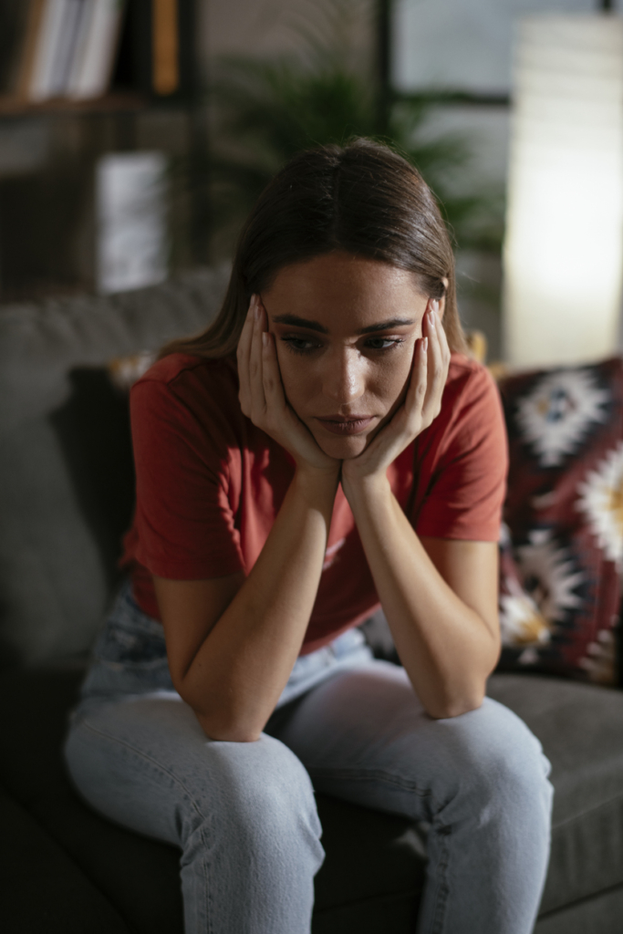 Lehangolt, kedvtelen nő ül az ágy szélén