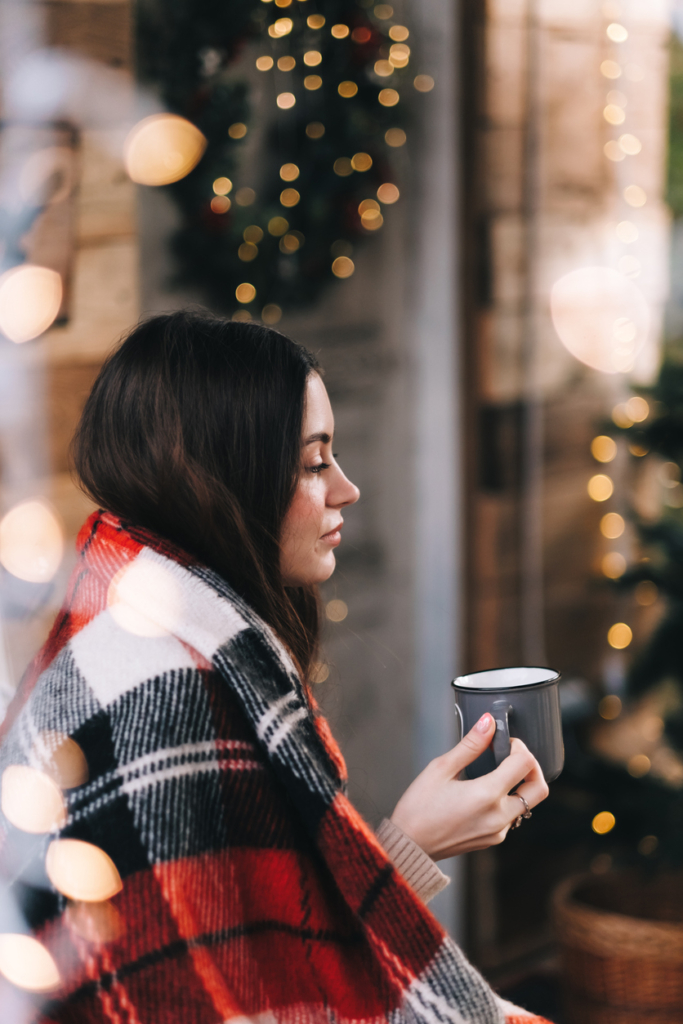 Fiatal nő egy kockás plédben, kezében kávésbögre