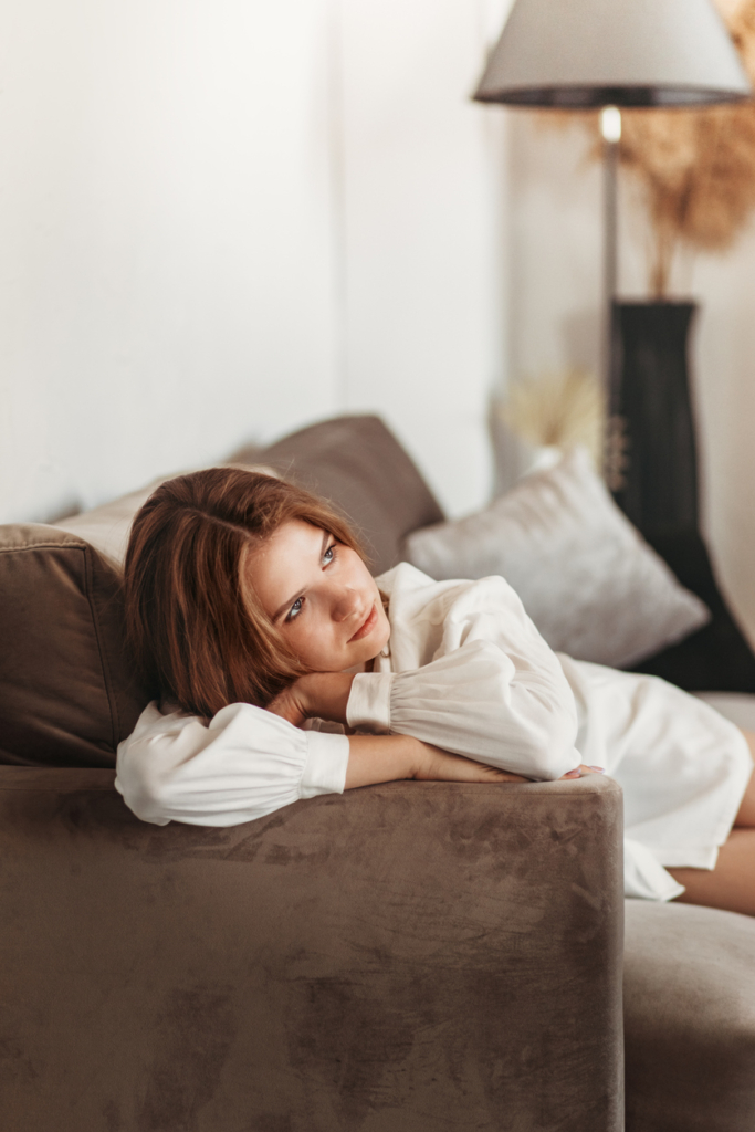 Fiatal nő elgondolkodva pihen a szófa karfáján