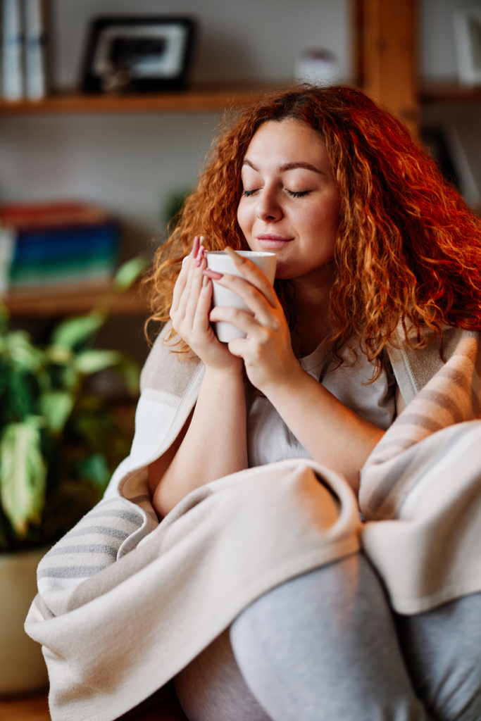 Nő élvez egy csésze teát a kanapén