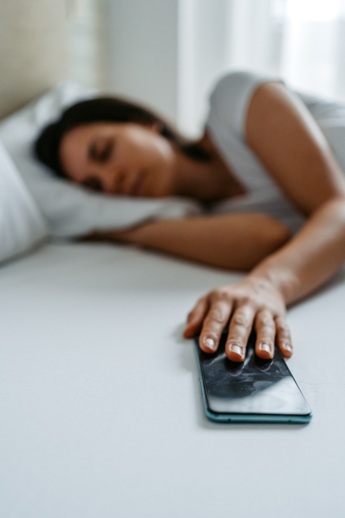 Nő alvás közben az egyik kezével fogja a mobiltelefonját