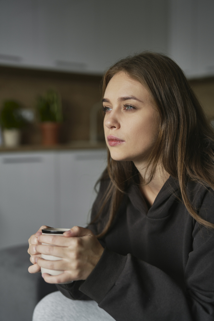 Közeli kép egy nőről, aki kávét iszik otthon