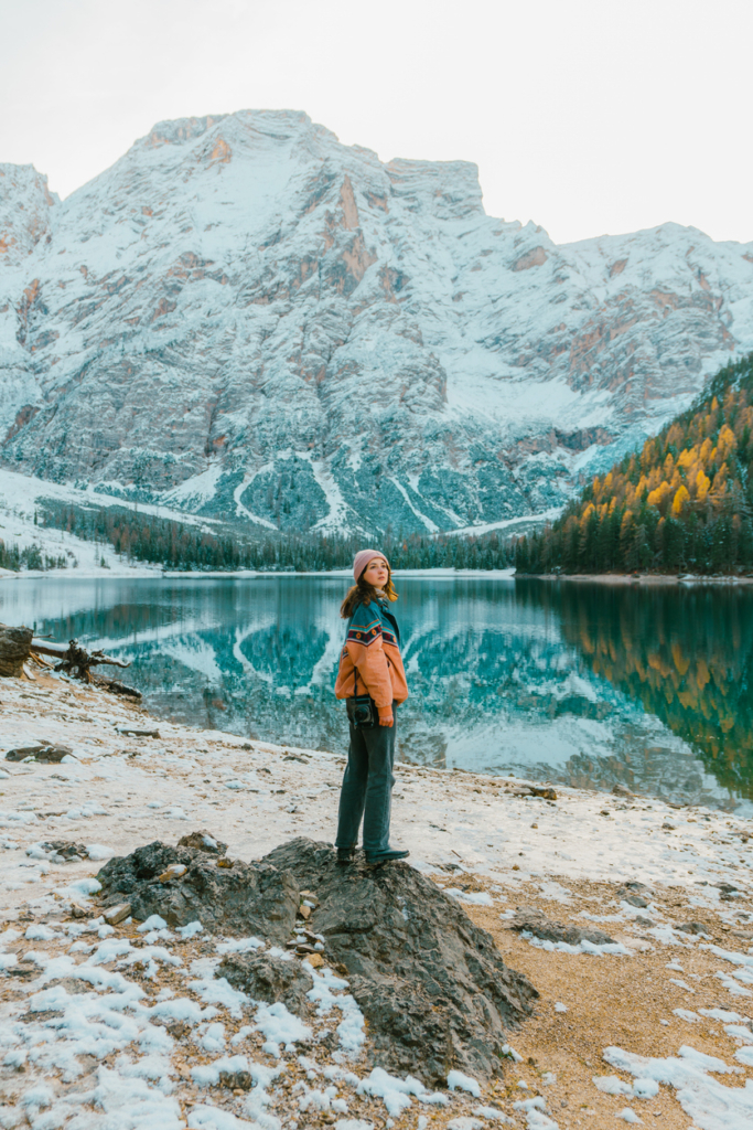 Nő kirándulás közben hatalmas hegyek és egy hegyi tó mellett