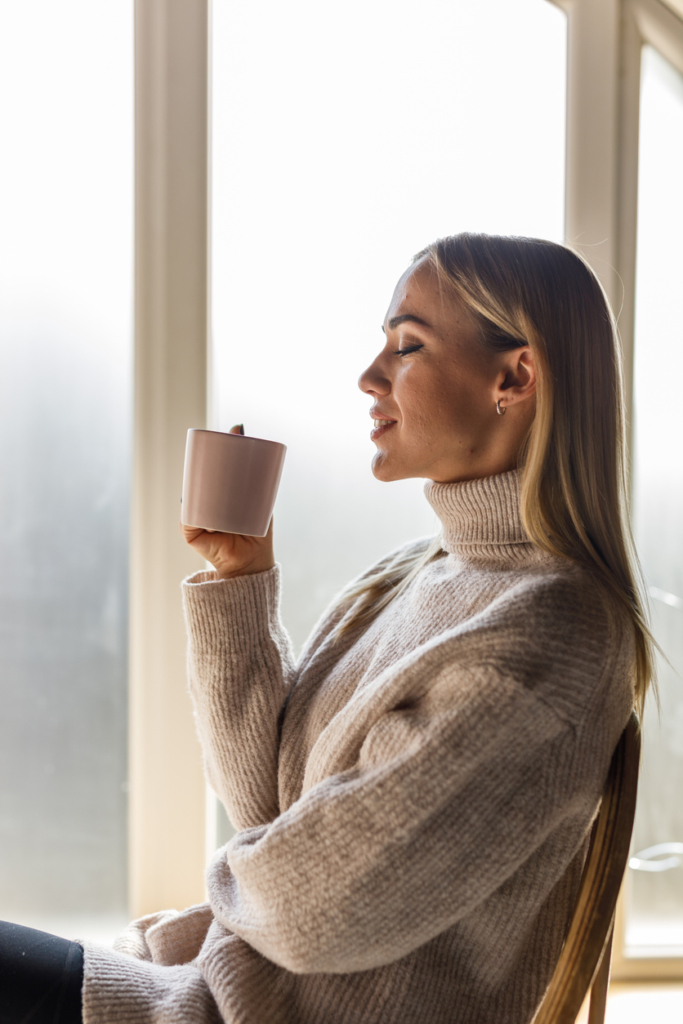 Nő élvezi a reggeli csésze kávéját az ablaknál
