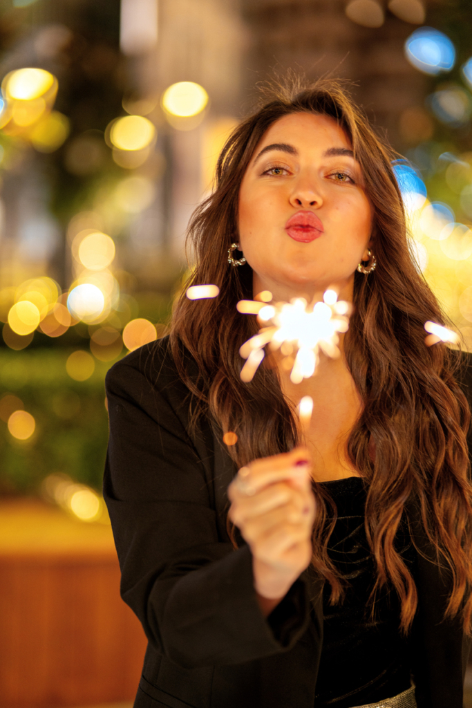 Fiatal lány csillagszóróval a kezében, mögötte ünnepi fények