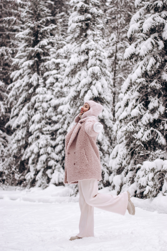 Nő téli ruhában, fél lábon egyensúlyozik a hóban