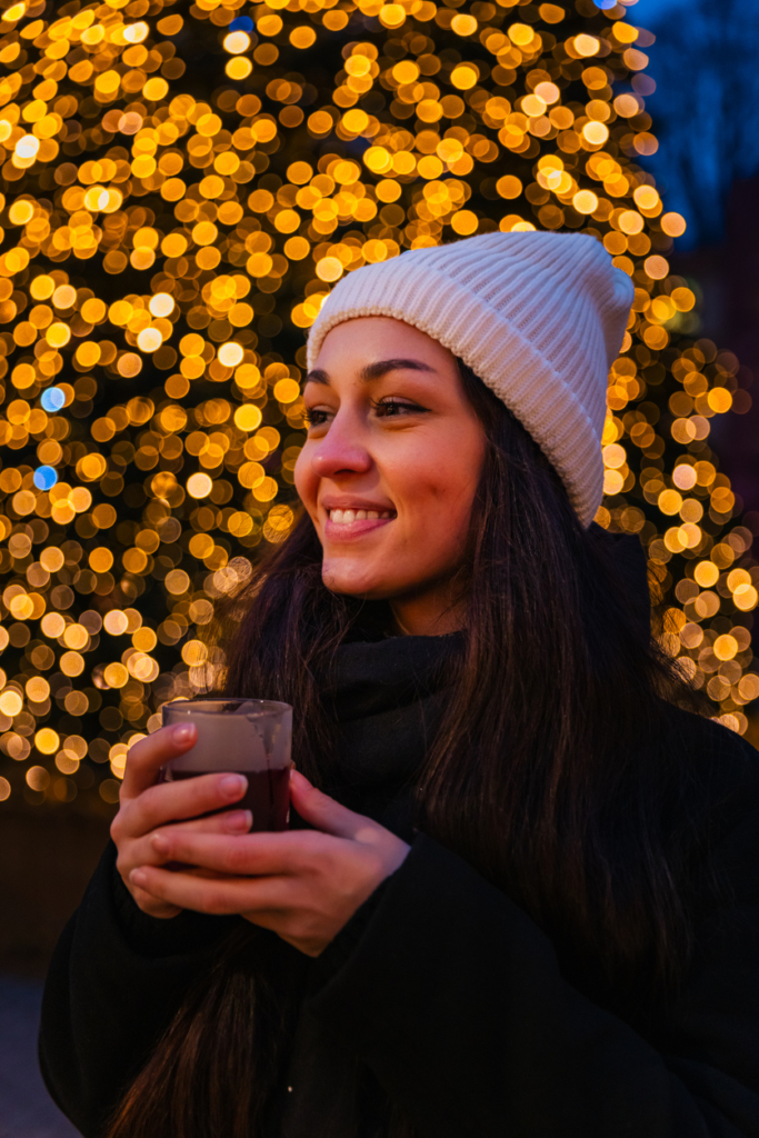Lány élvezi a téli forró csokit este, a szabadtéri fények előtt