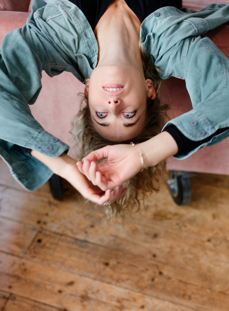 Nő unatkozik, közben fejjel lefelé csüng az ágyról