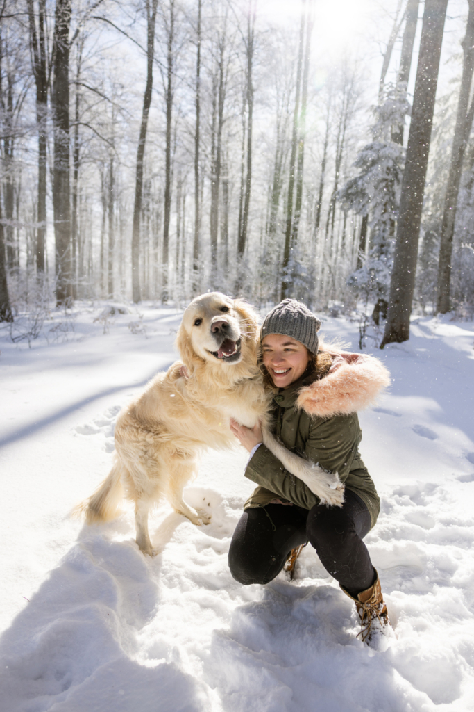 Nő a kutyájával játszik a hóban